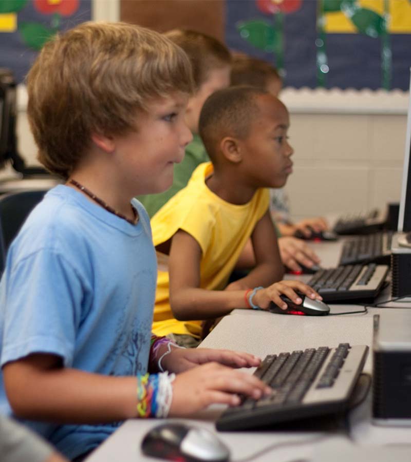 Various children are enjoying computer time in their computer lab.