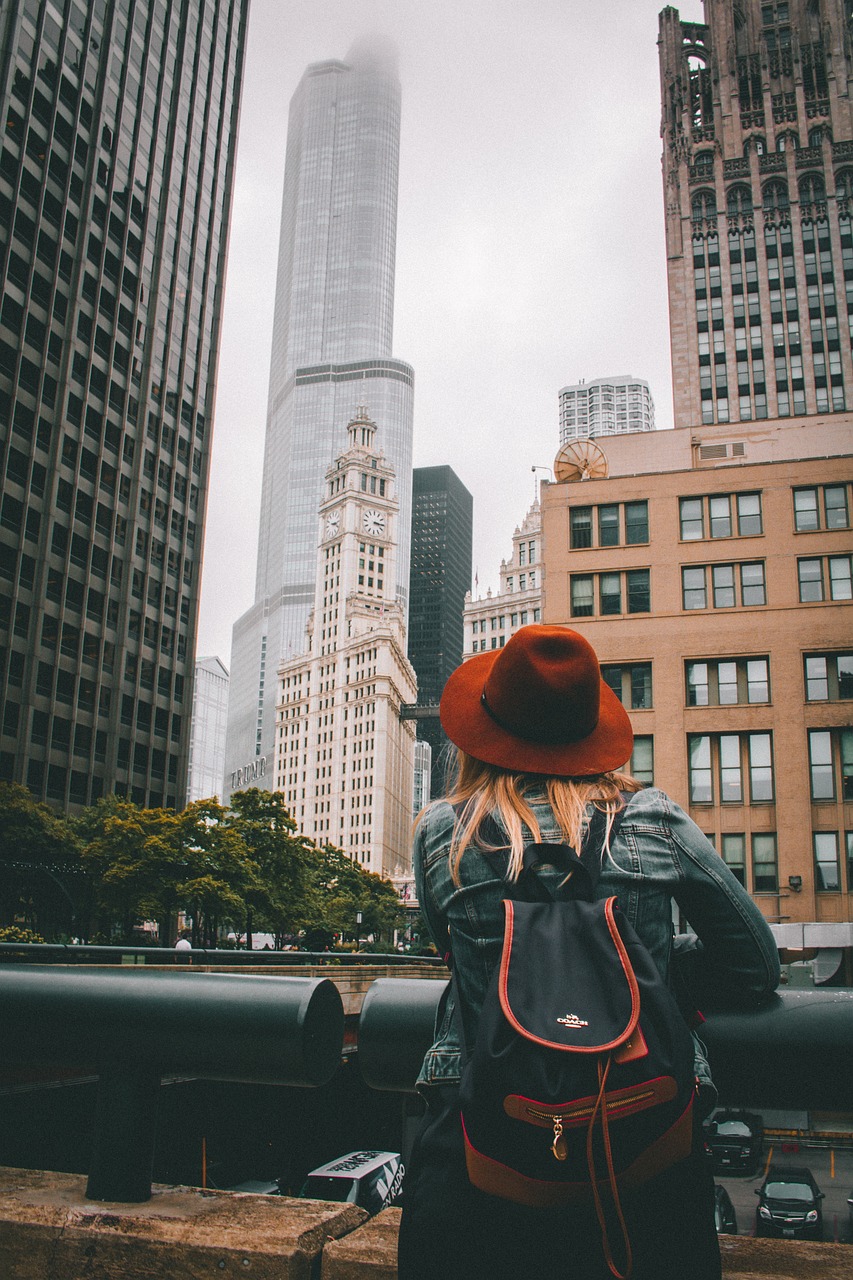A backshot of a tourist looking up past a barrier at stunning skyscrapers.